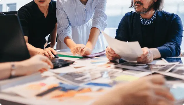 資料や写真を広げて、複数人で企画や戦略を検討している打ち合わせの様子